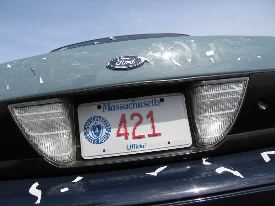 Ford Crown Victoria rear with Massachusetts license plate 421. Light blue trunk lid is scratched