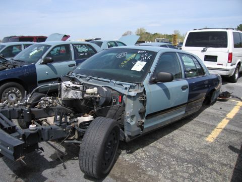 2001 Ford Crown Victoria - Junkyard vehicle, a 2001 Ford Crown Victoria, shows significant damage and missing parts.