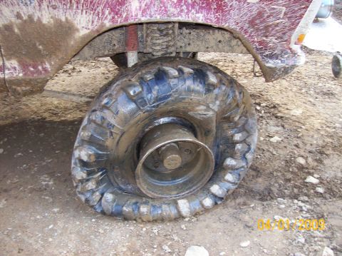 1978 Ford Bronco - A flat tire on a mud-covered 1978 Ford Bronco suggests off-road use.