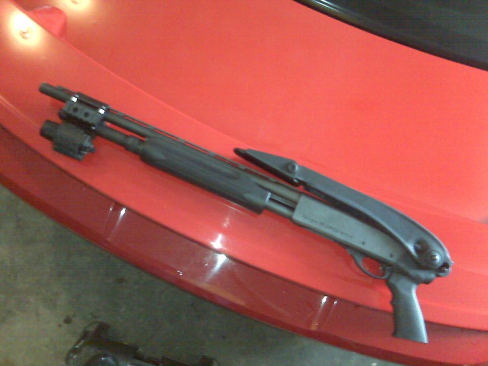 shotgun with flashlight on red car hood