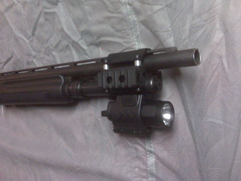 2004 Ford Mustang - A close-up view of a shotgun barrel with an attached tactical flashlight and rail system.