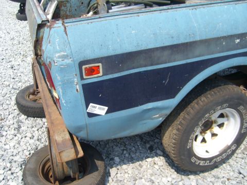 1994 Ford Bronco - Close-up of a dented blue pickup truck's rear quarter panel, showing a '1988 Scout' sticker.