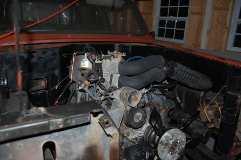 1994 Ford Bronco - The engine bay of an orange vehicle is shown, with various mechanical parts and wiring visible.