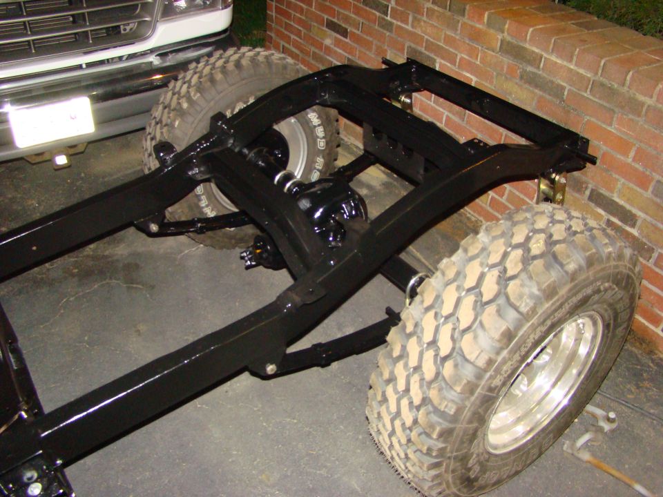 Black vehicle frame with large tires and suspension components visible