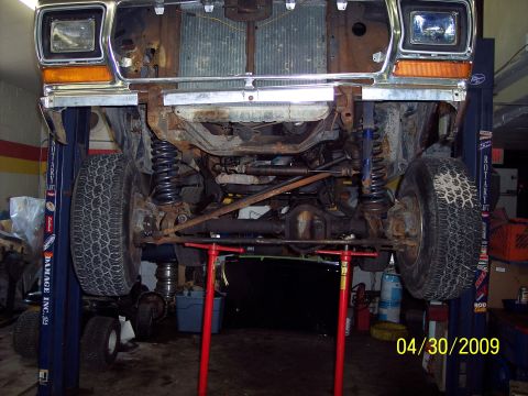 1979 Ford Bronco - The front suspension and drivetrain of a 1979 Ford Bronco are visible as the vehicle is raised on a lift for service.
