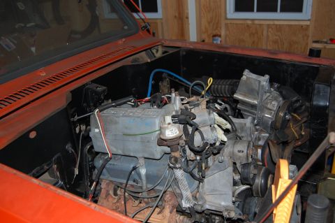 1994 Ford Bronco - The engine compartment of an orange vehicle is shown, with various mechanical parts and wiring.