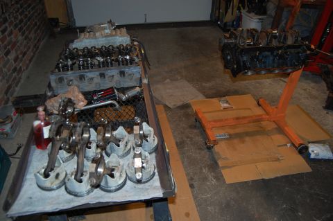 1994 Ford Bronco - Engine block and pistons with connecting rods are laid out on a table, likely for repair or rebuilding.
