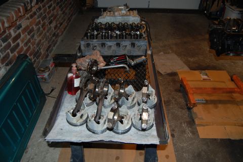 1994 Ford Bronco - Engine components laid out on a workbench, including a block and pistons with connecting rods.