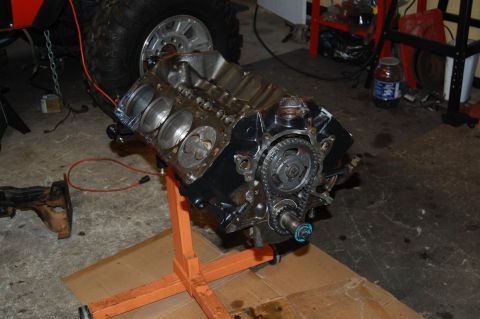 1994 Ford Bronco - Engine block on a stand, with a large tire and vehicle parts in the background.