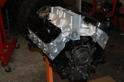 1994 Ford Bronco - A V8 engine is shown on an orange stand, with a red stand and a large tire visible in the background.