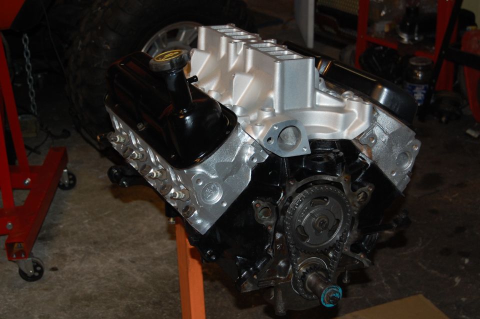 V8 engine on an orange stand, with a red stand and tire in background