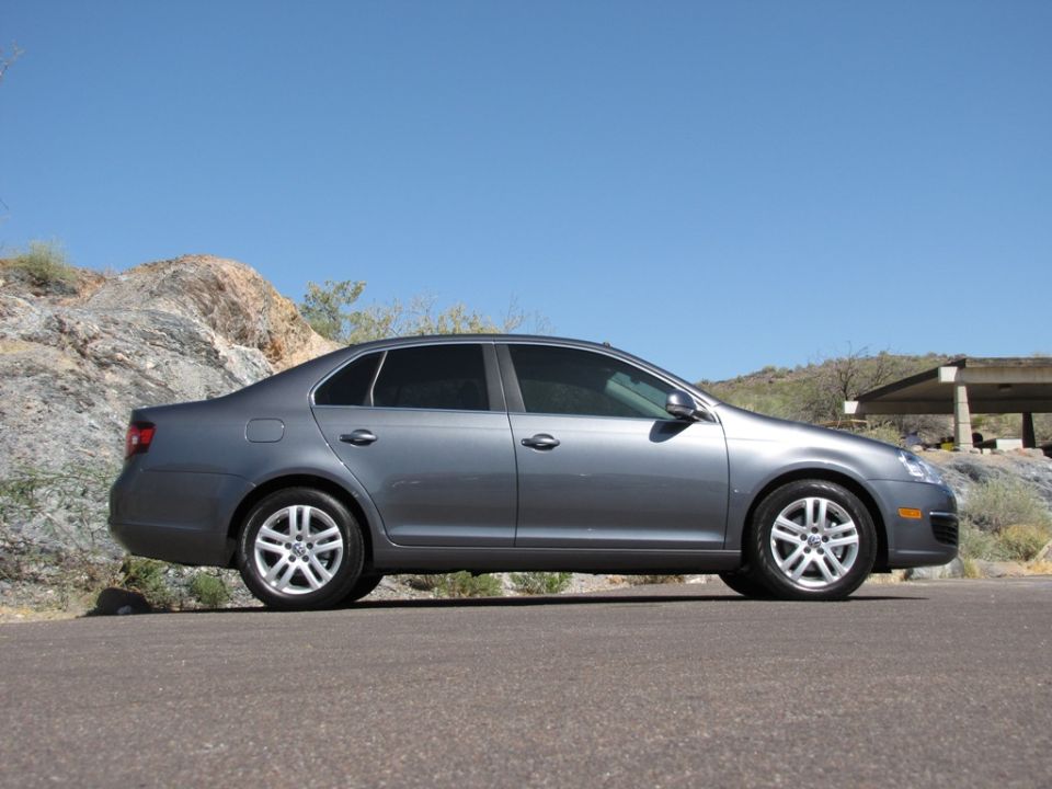 Gray Volkswagen Jetta sedan, driver-side profile, parked in a desert setting.