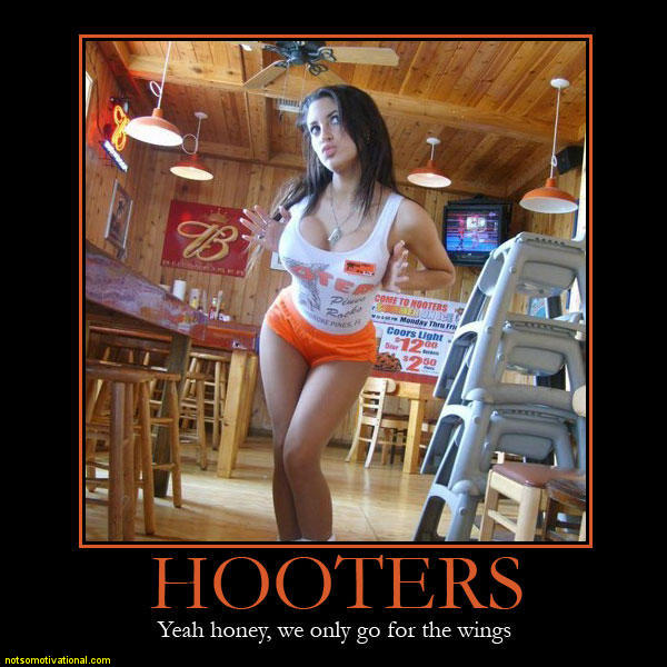 Woman in white tank top and orange shorts stands in a Hooters restaurant