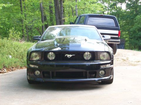 2007 Ford Mustang - Front view of a black Ford Mustang with a prominent hood scoop, parked outdoors.