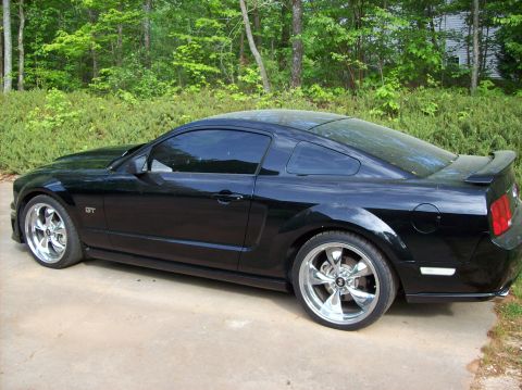 2007 Ford Mustang - Side profile of a black 2007 Ford Mustang GT coupe with custom wheels.