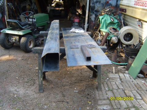 1989 Ford Bronco - Metal fabrication materials and a riding mower are visible in a cluttered workshop setting.