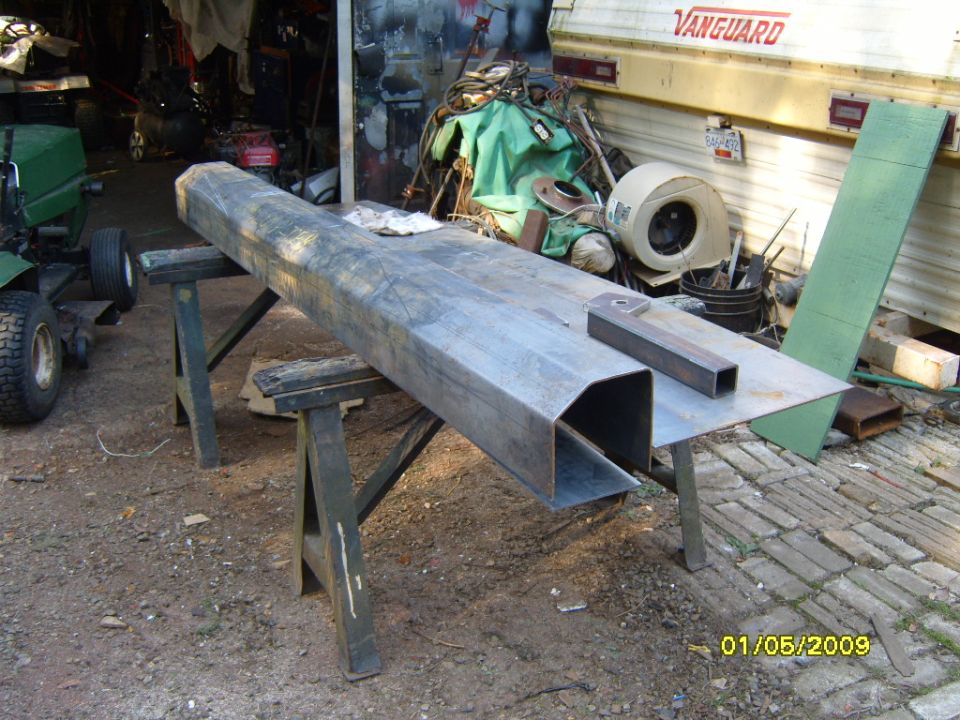 Metal bumper part on sawhorses, with a Vanguard trailer in background