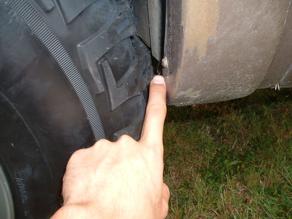 Finger pointing at narrow gap between large tire tread and fender edge
