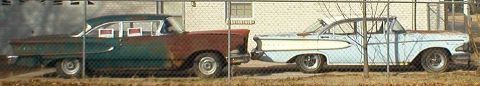 1983 Ford Bronco - Two vintage sedans, one green and one blue, sit behind a fence, showing significant rust and wear.