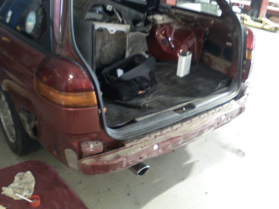 Rear of dark red station wagon with tailgate open and bumper removed