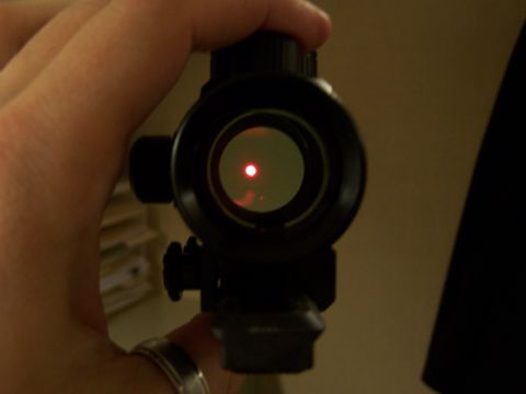 1986 Ford Bronco - Close-up of a red dot sight being held, showing the aiming reticle.