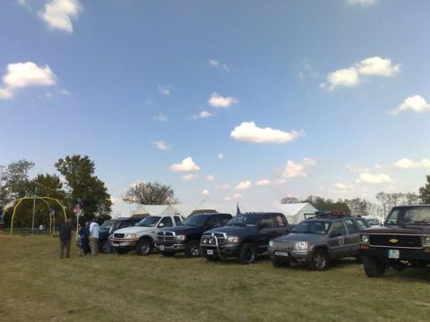 1991 Ford LTD Crown Victoria - A variety of trucks and SUVs are parked on a grassy field during an outdoor event.