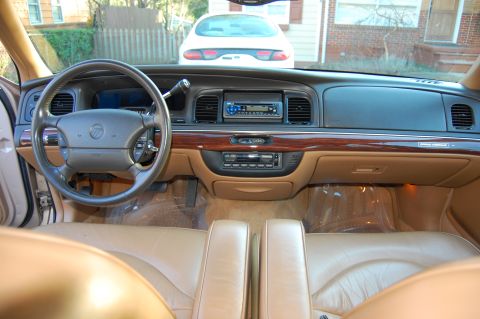 1996 Mercury Grand Marquis - The interior of a car with tan leather seats and wood accents on the dashboard. Another vehicle is visible outside.