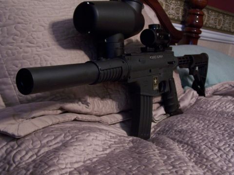 1986 Ford Bronco - A tactical-style paintball gun is displayed on a bed, an attached scope and extended barrel.