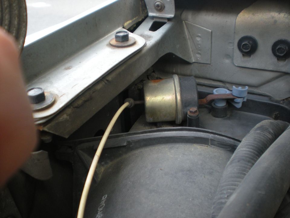 Engine bay component with a yellow wire and a brass-colored cylinder