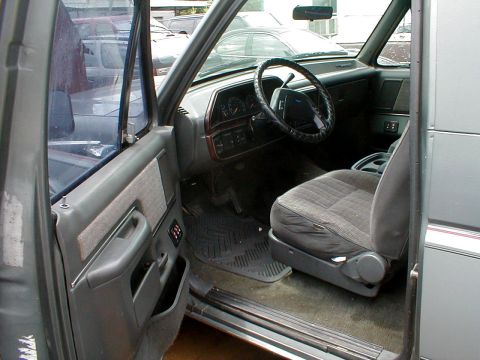 1983 Ford Bronco - The interior of a gray SUV is visible, with a focus on the driver's seat and dashboard area.