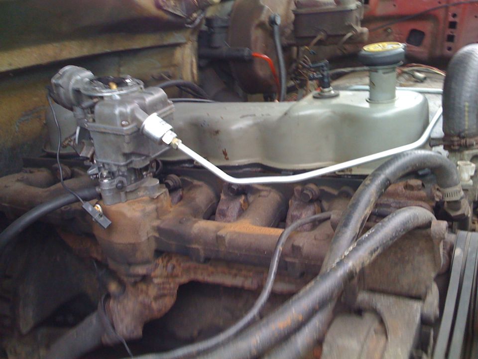 Older inline engine with carburetor and intake mounted in engine bay