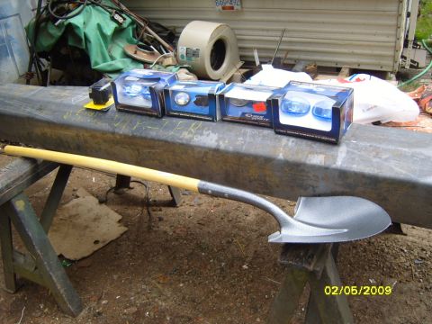 1989 Ford Bronco - A shovel rests on sawhorses in front of a metal beam. Several boxes of automotive lights are on the beam, along with a black electrical com…