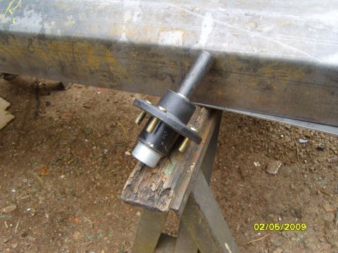 1989 Ford Bronco - A black trailer hub assembly with four gold studs is mounted on a metal beam supported by a wooden sawhorse. The beam appears to be part of…