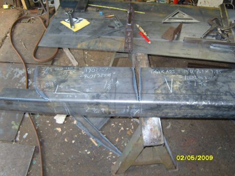 1989 Ford Bronco - A close-up view of metal fabrication work, likely in a workshop. The image shows a long metal beam with chalk markings and calculations, po…