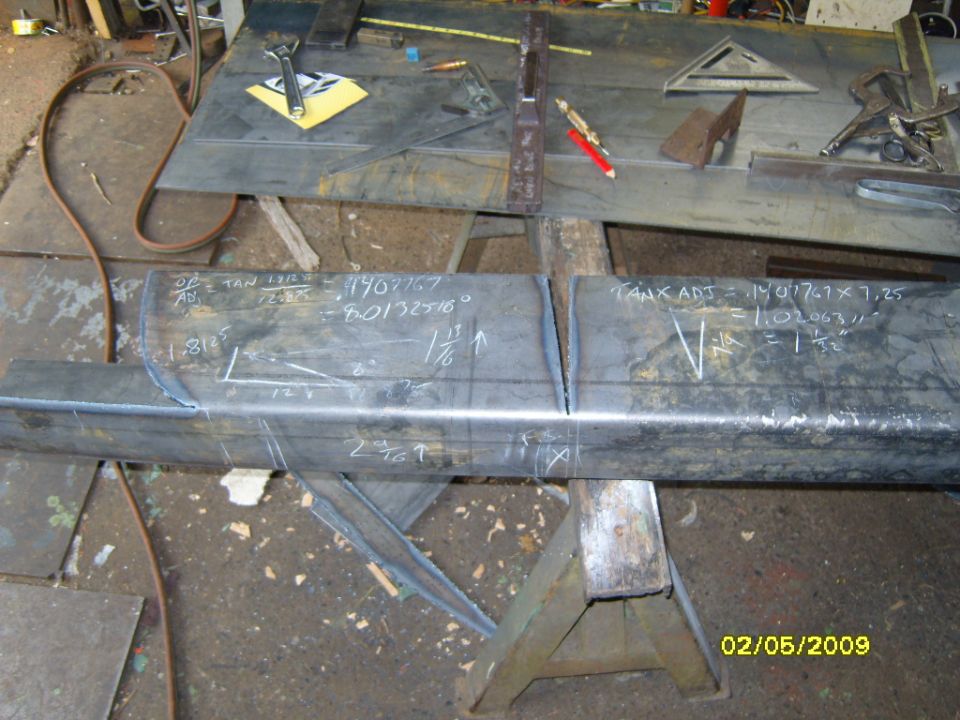 Metal beam with chalk markings and calculations in a workshop setting.