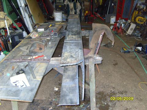 1989 Ford Bronco - A workshop scene shows various metal fabrication tools and materials, including large steel sheets, a metal bender, and measuring tools, la…