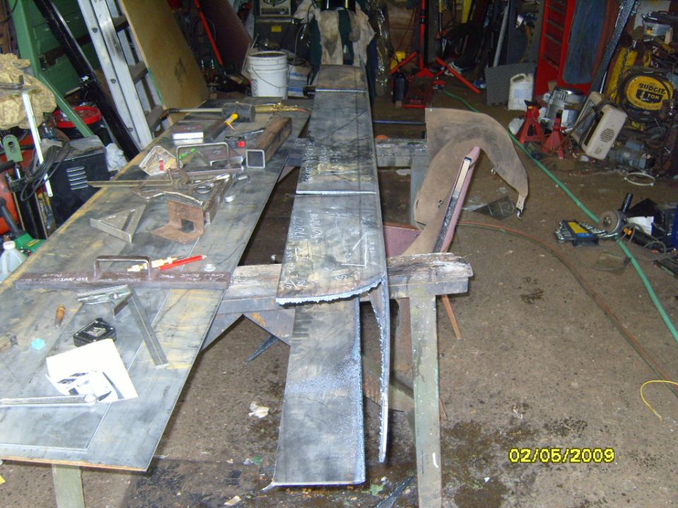 Workshop with metal fabrication tools and materials, including steel sheets and a metal bender.