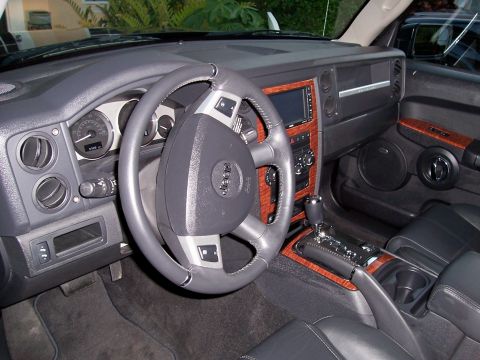 1978 Ford Bronco - The interior of a Jeep Commander SUV features a wood-grain trim, a leather-wrapped steering wheel with Jeep branding, and a center console…