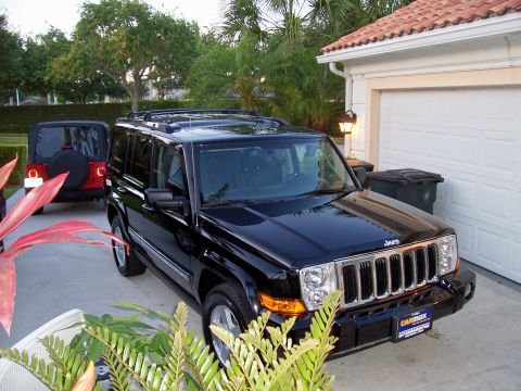 1978 Ford Bronco - A black Jeep Commander is parked in a driveway next to a red Jeep Wrangler. The Jeep Commander is in the foreground, facing the camera, wit…