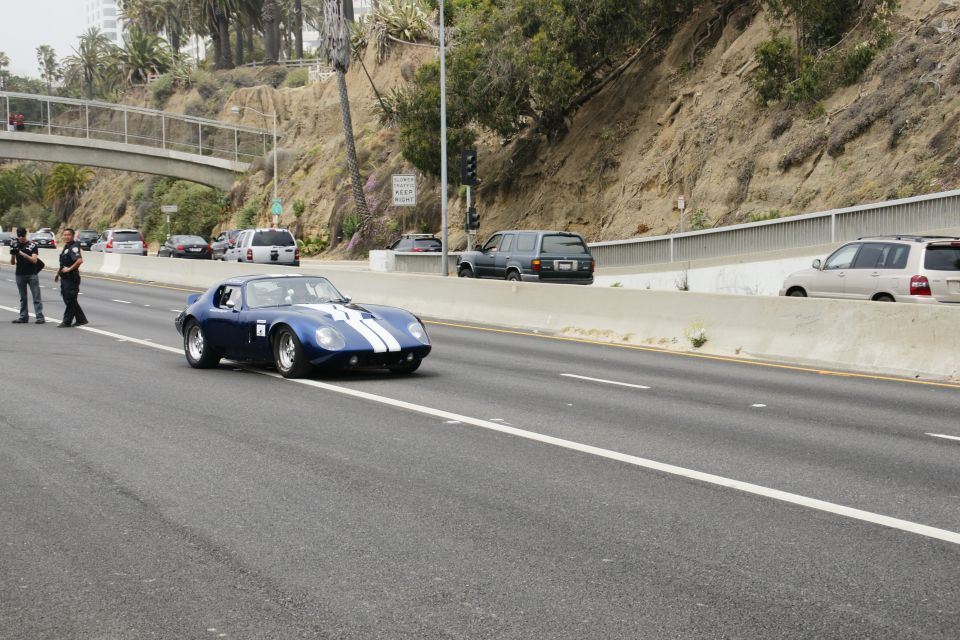 Blue and white classic sports car on highway with police officers on shoulder