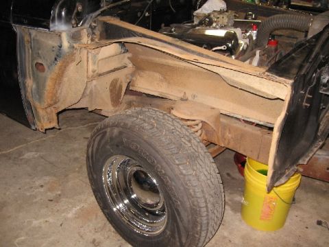 1966 Ford F-100 - The front driver's side wheel well area of a black classic vehicle is shown, with the fender removed, revealing rusty inner body panels and…