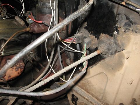 1966 Ford F-100 - A close-up view of the engine bay of a classic truck, showing brake lines, wiring harnesses, and a rusty firewall.