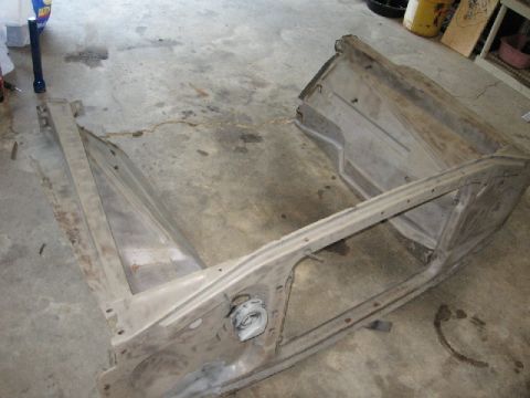 1966 Ford F-100 - The bare metal frame of a classic truck front end, possibly a 1966 Ford F-100, sits on a concrete garage floor. The frame appears to be dis…