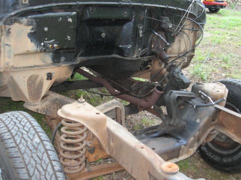 1966 Ford F-100 - The chassis and engine bay of a classic pickup truck are shown, with the front tire and suspension components visible. The vehicle appears…