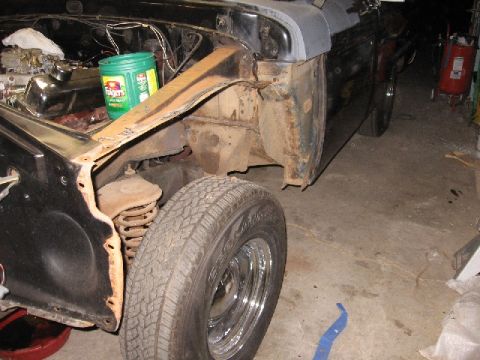 1966 Ford F-100 - The front fender of a vehicle is removed, revealing the engine bay and a tire.