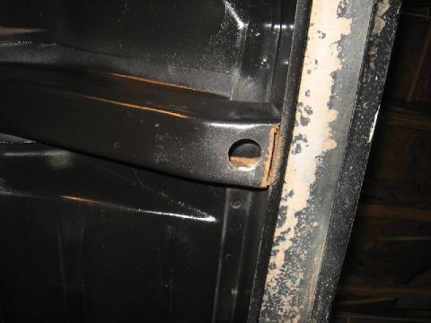 1966 Ford F-100 - Close-up view of the underside of a vehicle frame, showing black paint and areas of rust.