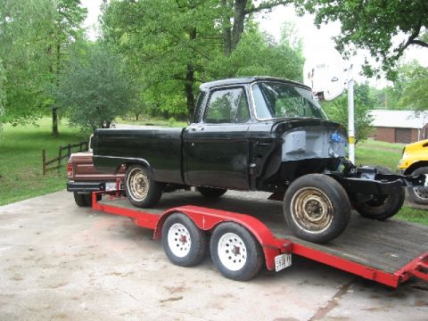 1966 Ford F-100 - A black 1966 Ford F-100 pickup truck is being transported on a red trailer, likely for restoration or paint preparation.