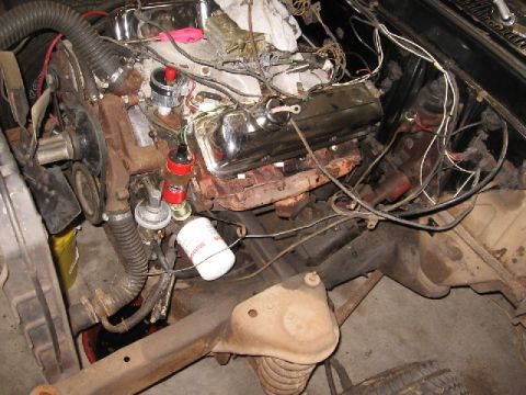 1966 Ford F-100 - The engine bay of a vehicle shows a V8 engine with chrome valve covers and an oil filter. Wires and hoses are visible throughout the compar…