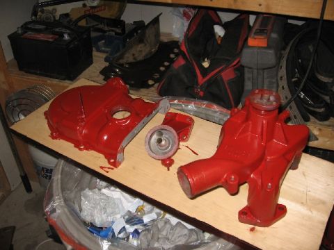 1966 Ford F-100 - Engine components, a valve cover and water pump, are laid out on a wooden surface, possibly for a rebuild or detailing project.
