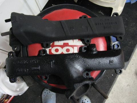 1966 Ford F-100 - Engine exhaust manifolds shown resting on a red tool accessory.